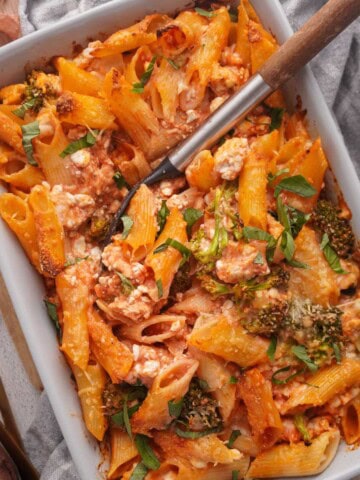 A baking dish with cottage cheese pasta bake inside and a spoon at the side.