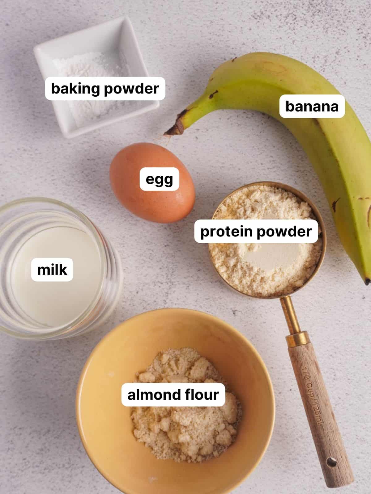 All the ingredients laid out for this protein pancake bowl recipe. It includes a banana, egg, almond flour and protein powder. 