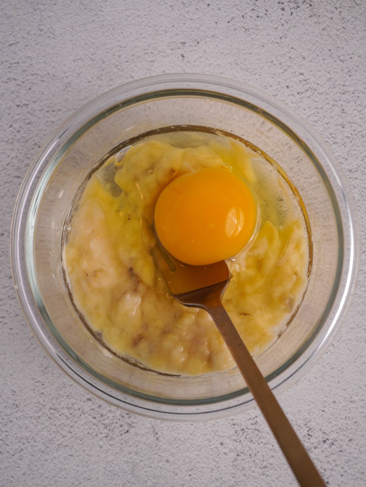 A glass bowl with mashed banana and egg for this protein pancake bowl recipe.