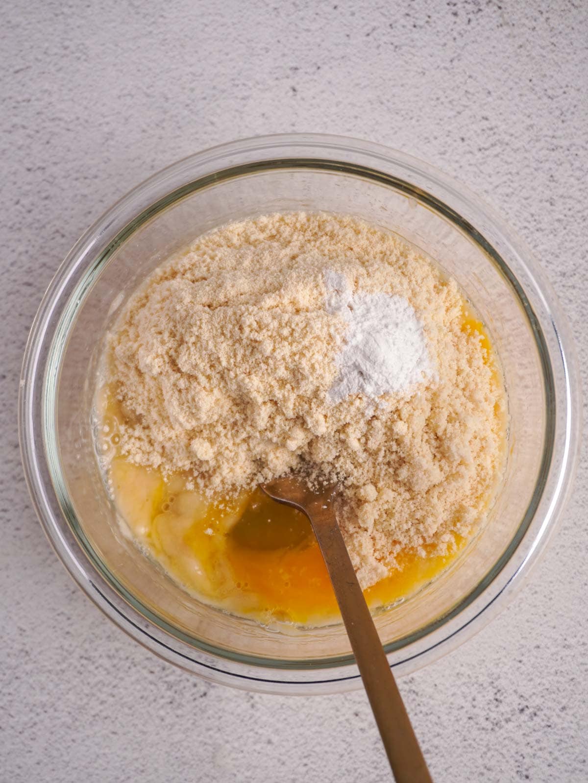 A glass bowl with mashed banana and almond flour.