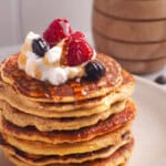 A stack of protein pancakes with greek yogurt, berries and honey drizzled on top.