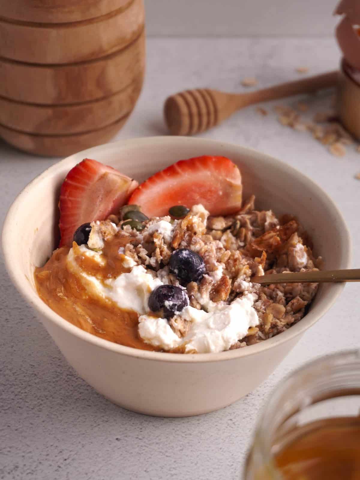 A bowl of scrambled oats with greek yogurt, peanut butter and berries on top. 