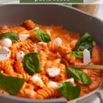 A skillet filled with pasta and a creamy cottage cheese pasta sauce topped with fresh mozzarella and torn basil leaves.