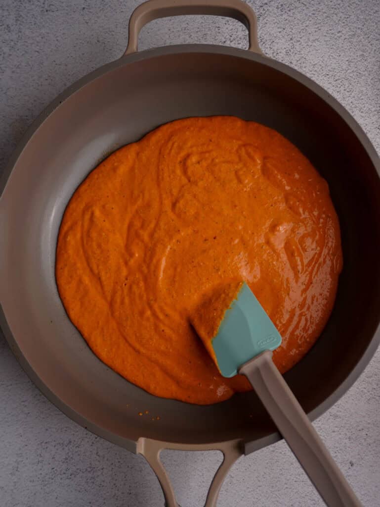 A skillet with a creamy red sauce inside it and a spatula sticking out.