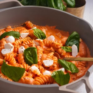 A skillet filled with pasta and a creamy cottage cheese pasta sauce topped with fresh mozzarella and torn basil leaves.